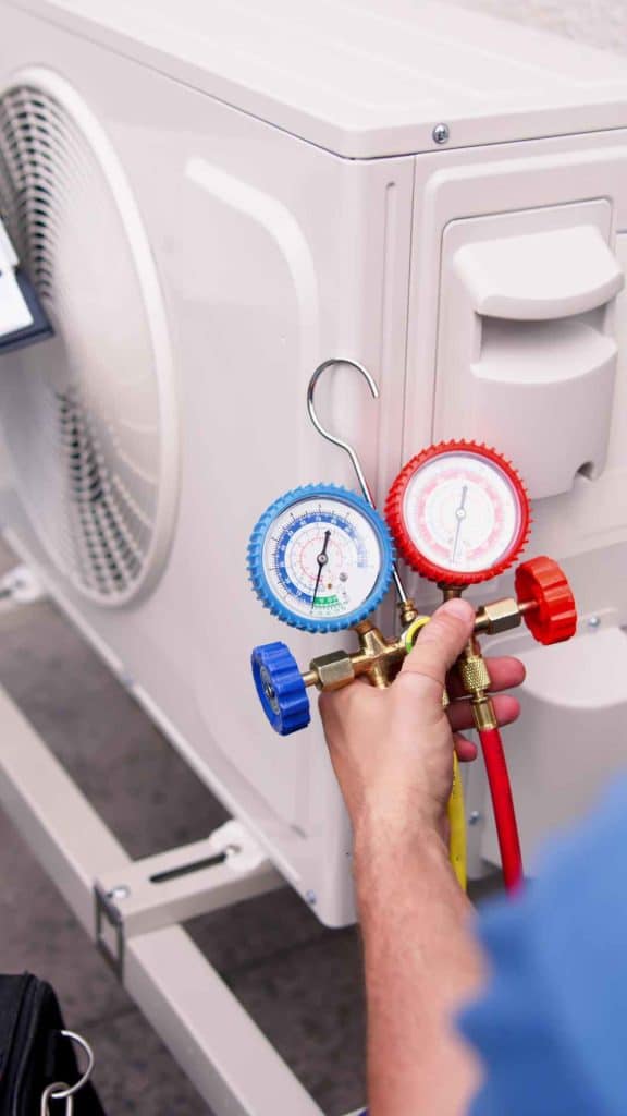 Richard's AC & Appliance Repair technician performing detailed AC diagnostics with manifold gauges during preventative maintenance on an outdoor unit.