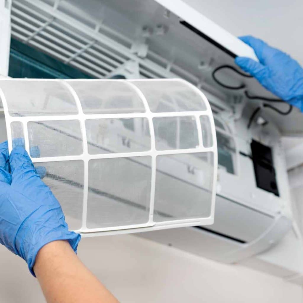 Replacing the clean air filter of a mini-split unit, crucial for summer maintenance.